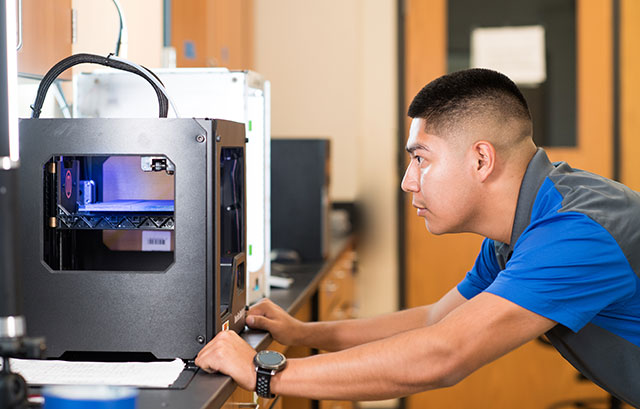 Photo shows student using 3-D printer