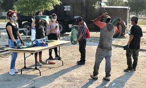 Members of the Immokalee Grassroots Movement give out bandanas and show recipients how to use them.