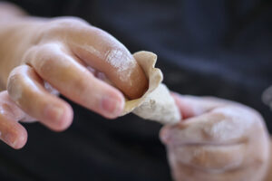 PHoto shows hands sculpting clay