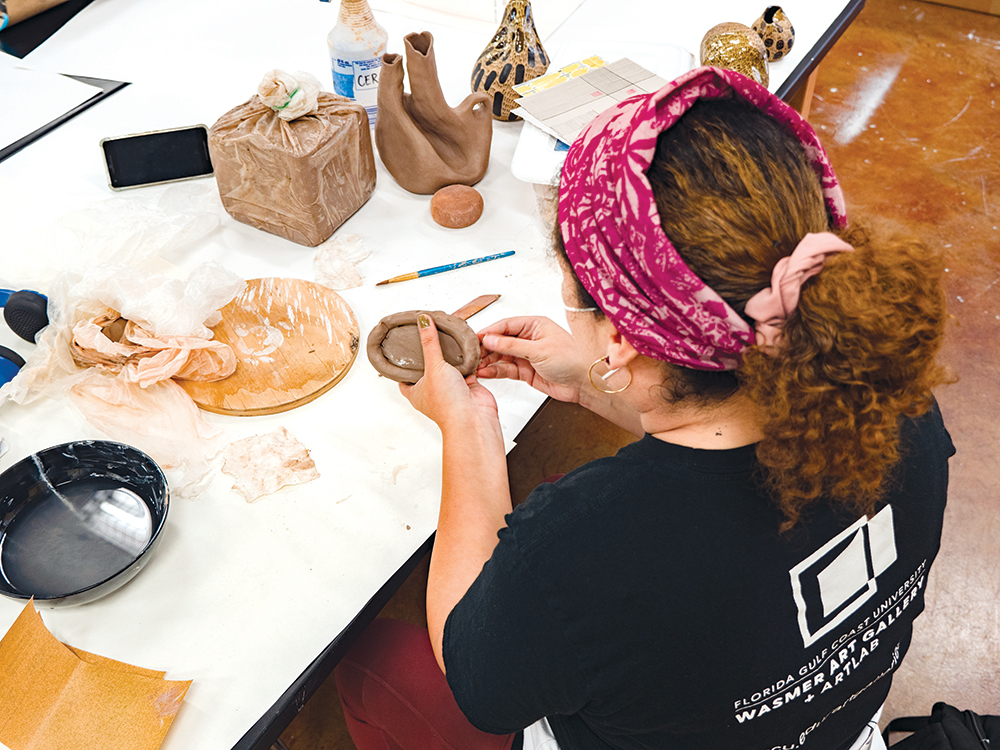 photo shows artist working with clay