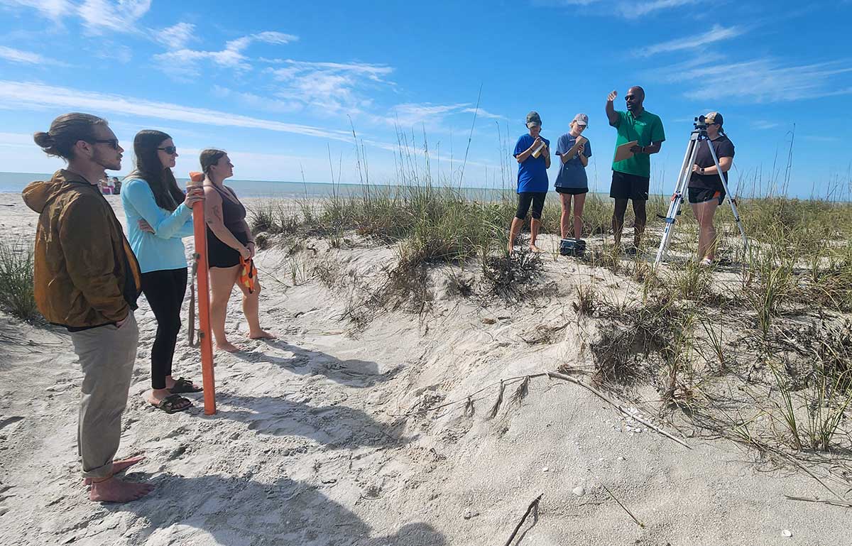 Professor conducting beach erosion study with students