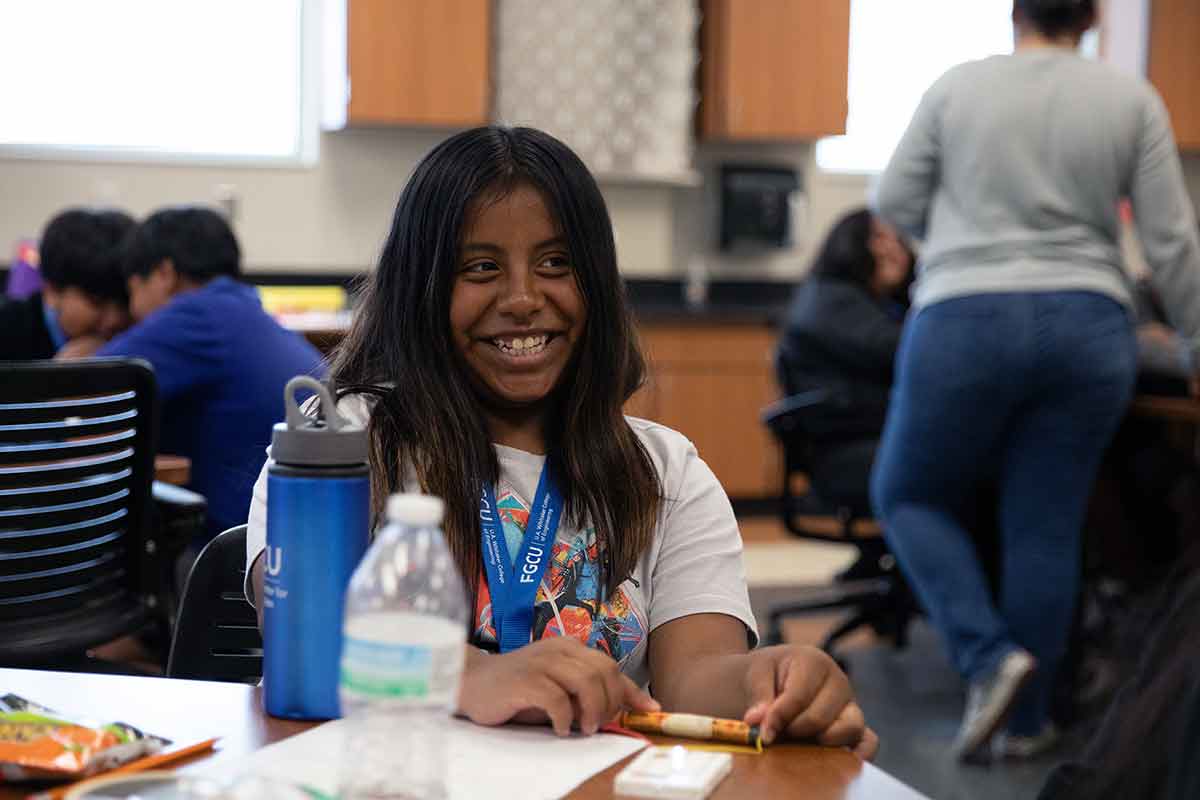 A smiling middle schooler in a college classroom