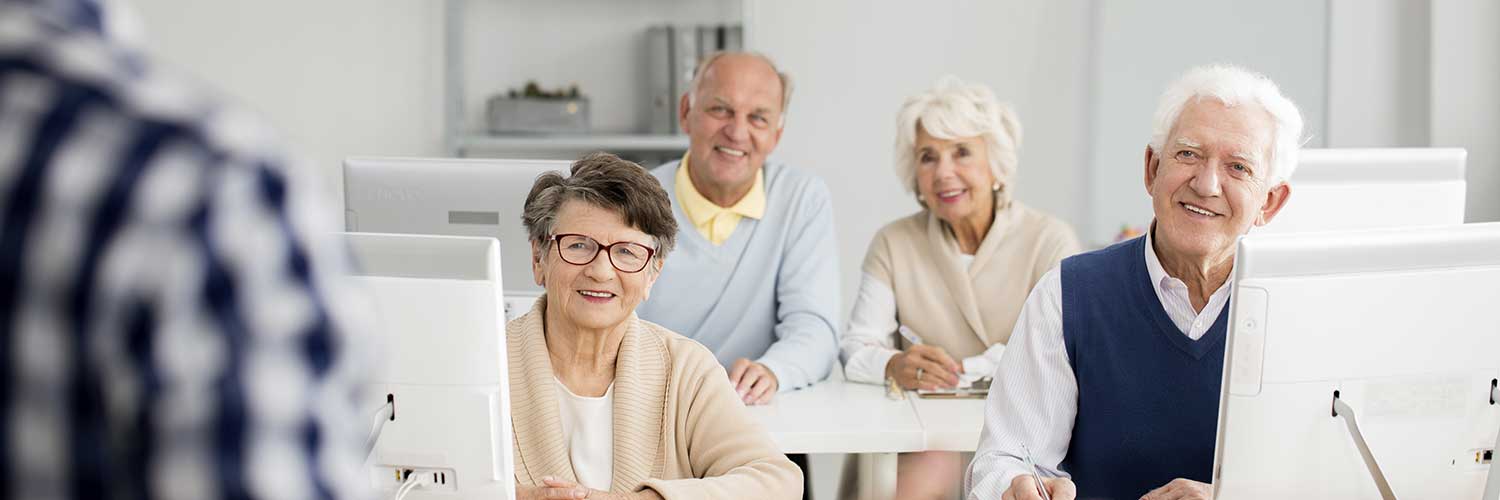 Older people sitting in a classroom listening to a speaker.