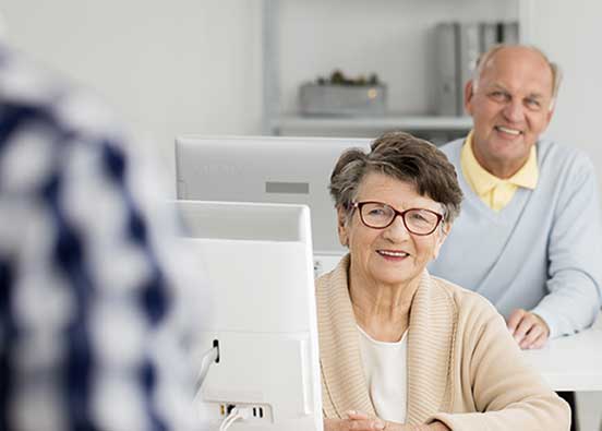 Older people sitting in a classroom listening to a speaker.