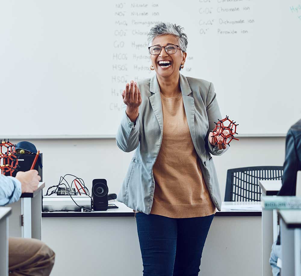 A woman standing in front of a classroom smiling.