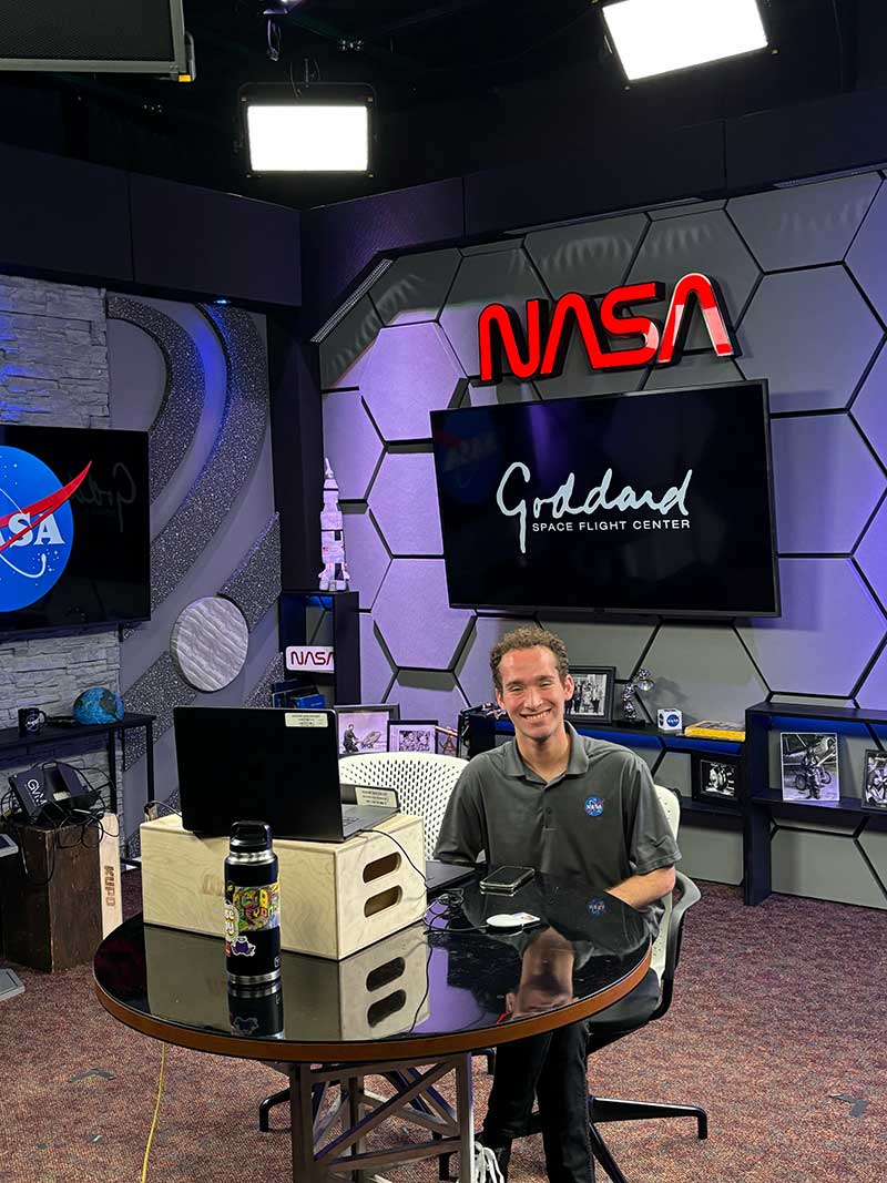 FGCU grad Brandon Cominsky sits in a chair in the communications studio at Goddard Space Flight Center.