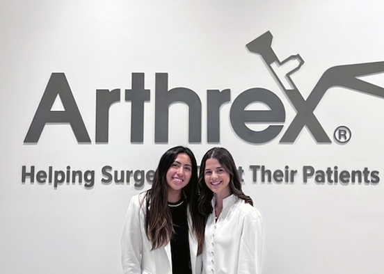 Two women standing in front of Arthrex business sign