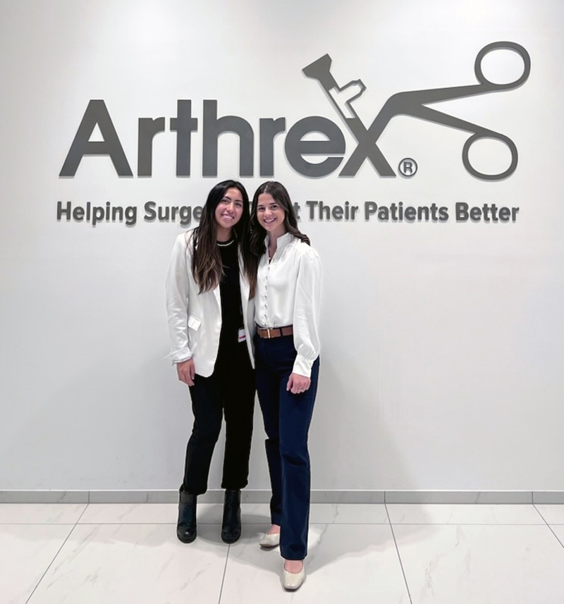 Two women standing in front of Arthrex business sign