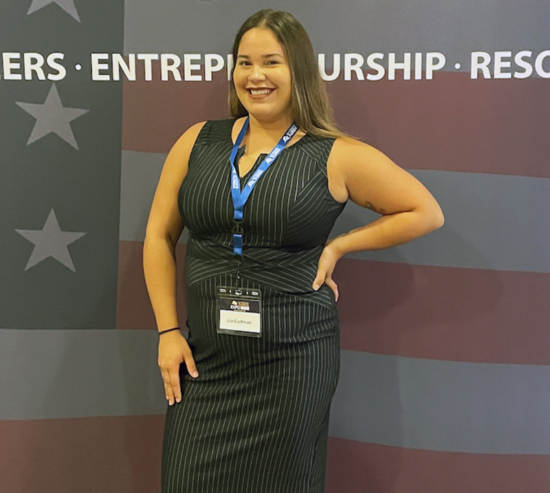 Woman in black dress standing in front of flag