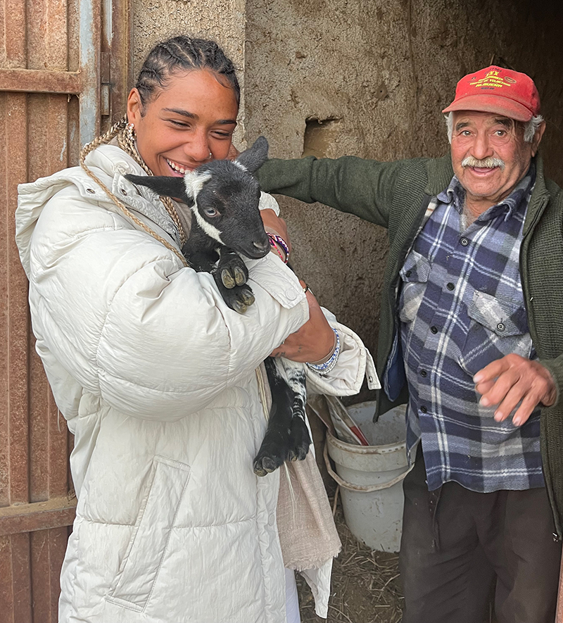 woman holding goat next to man on farm