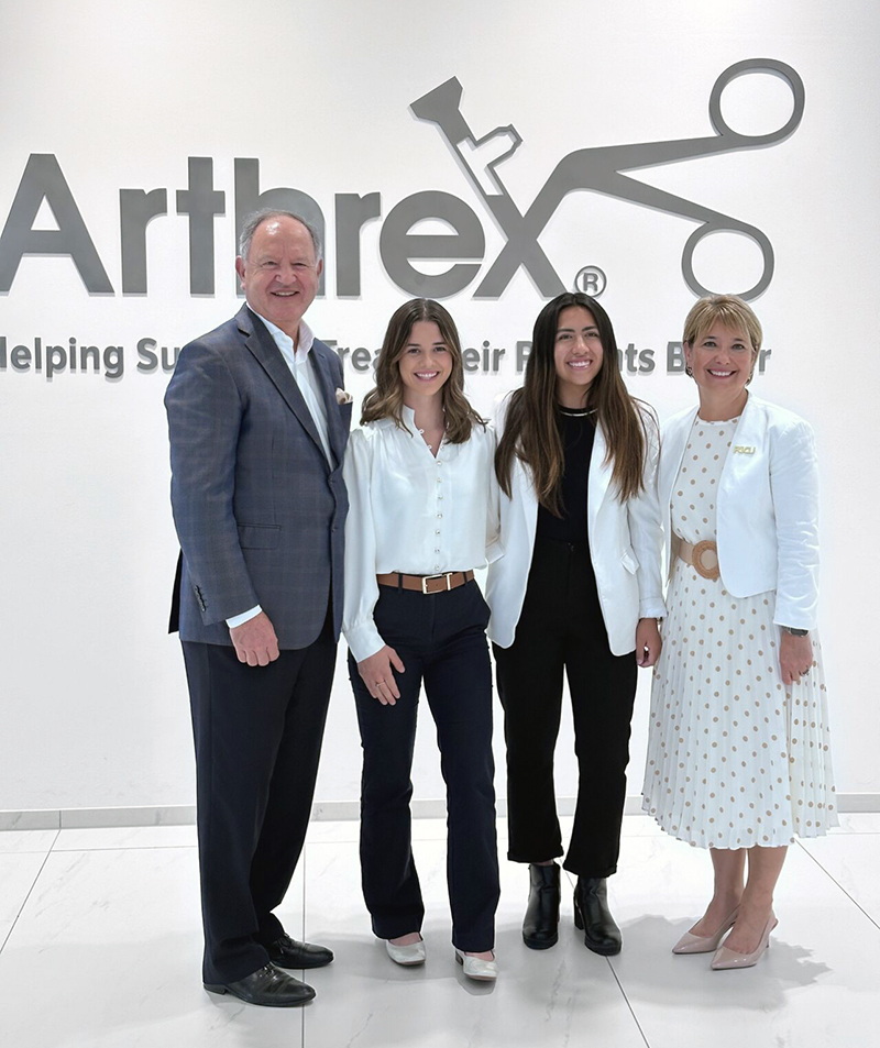 Man and three women standing in front of Arthrex business sign