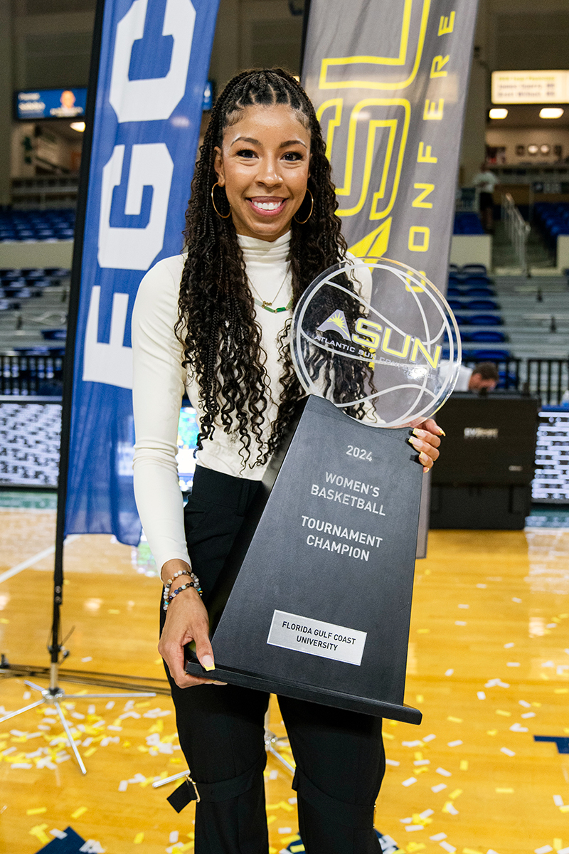 Woman holding a trophy on a basektball court