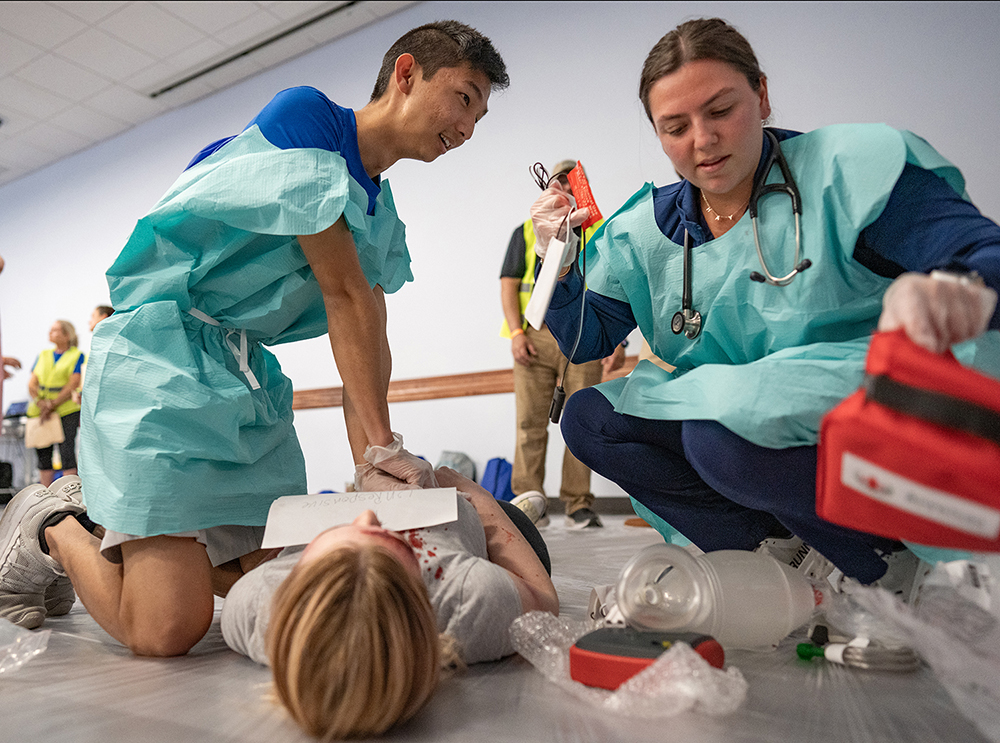 Two students treat a fake patient during an emergency simulation