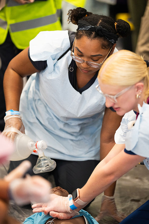 Two women practice CPR on a dummy during a disaster simulation.