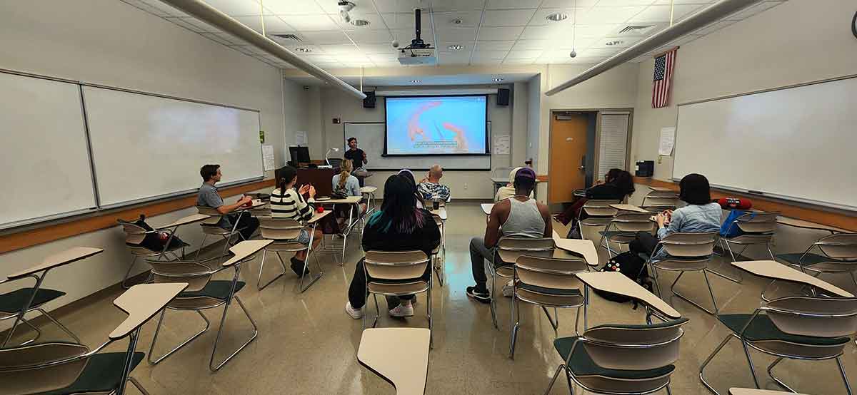 A wide angle photo of students in a classroom as viewed from behind