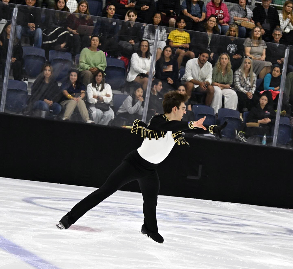 Man in black costume ice skating in arena