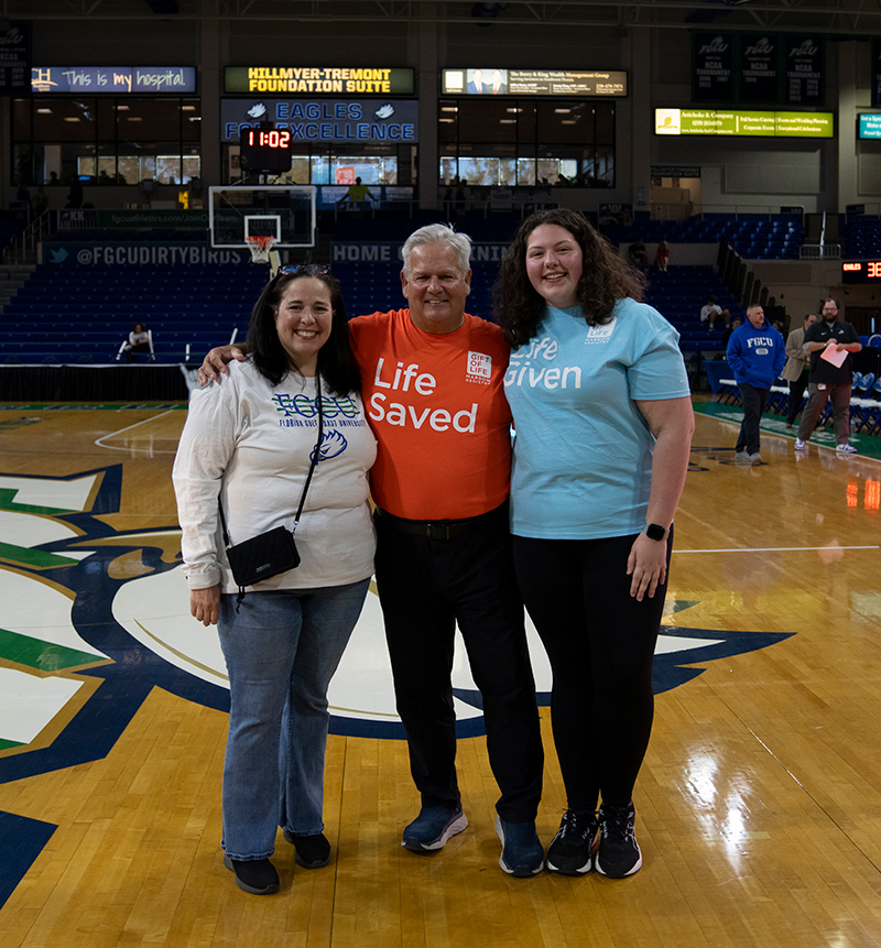 two women and one man standing on basketball court