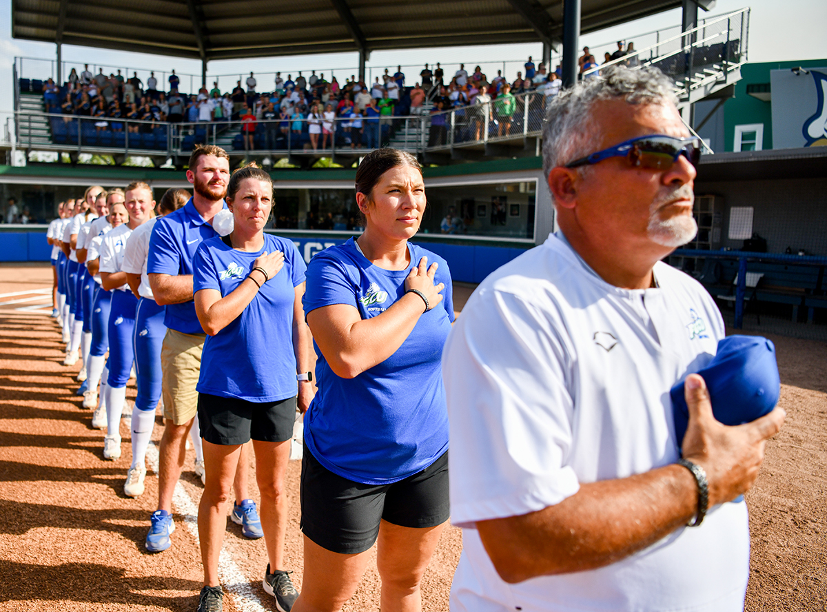 softball team and coach standing in line on ballfield