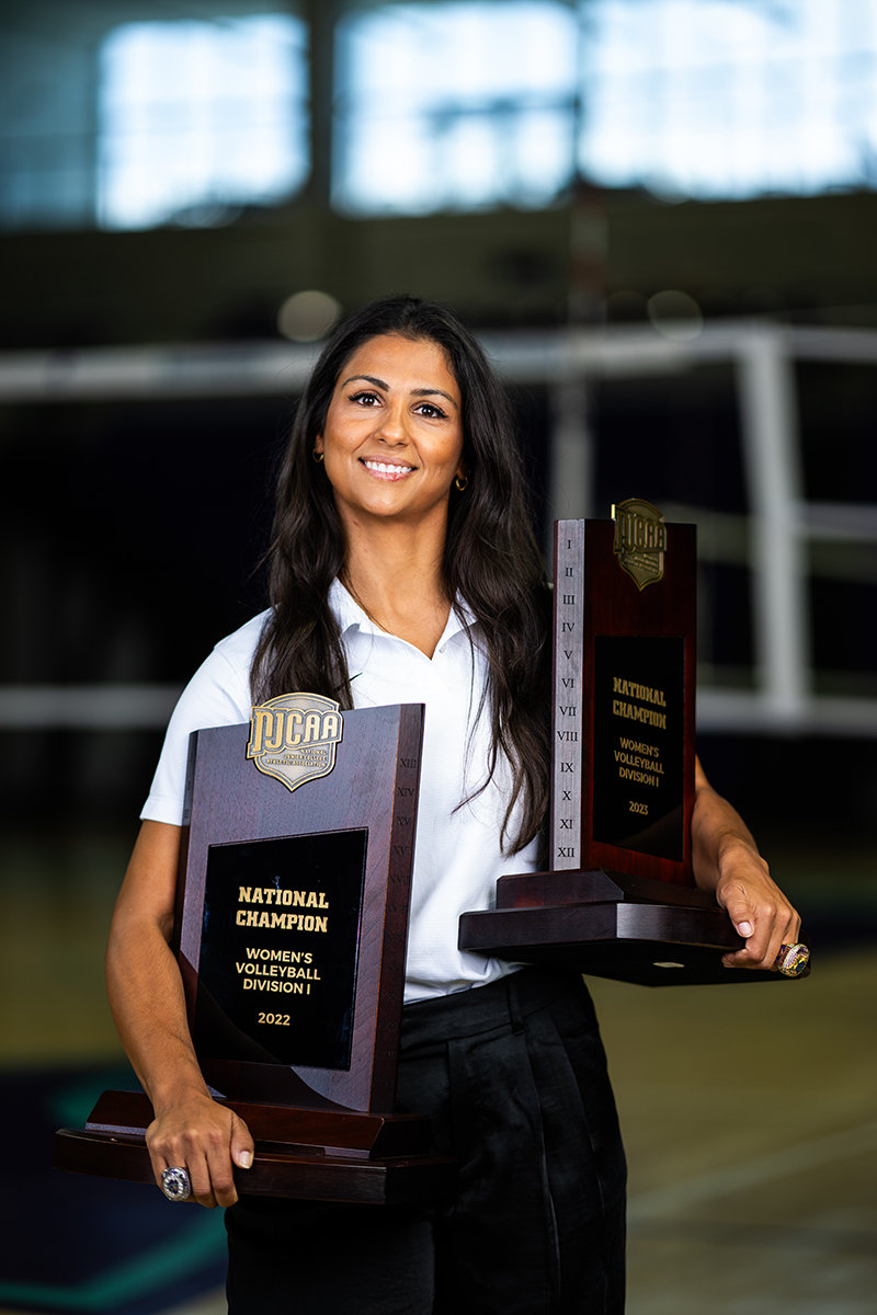 Woman in white shirt holding two trophies