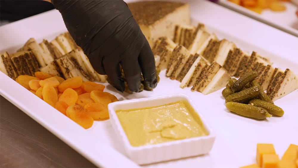 Gloved hand arranging food on a platter