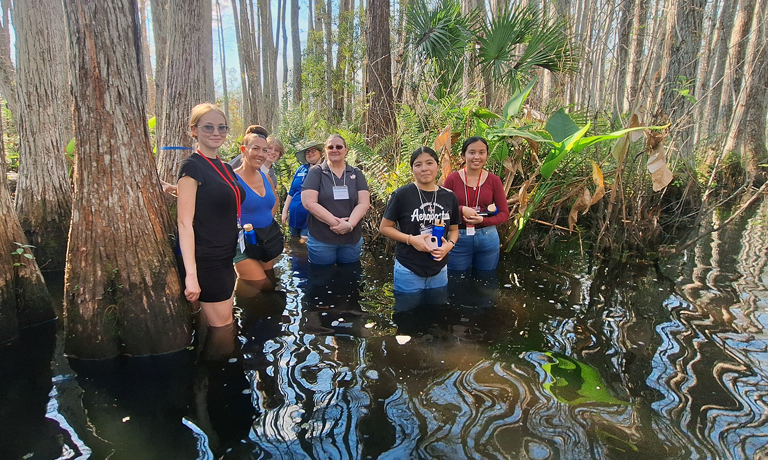 Group of students standing in water by cypress trees