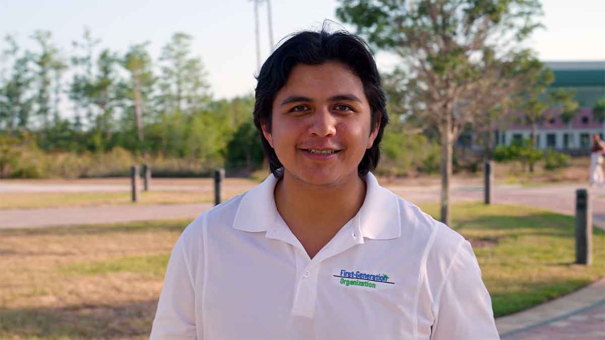 A man in a white polo shirt stands outdoors