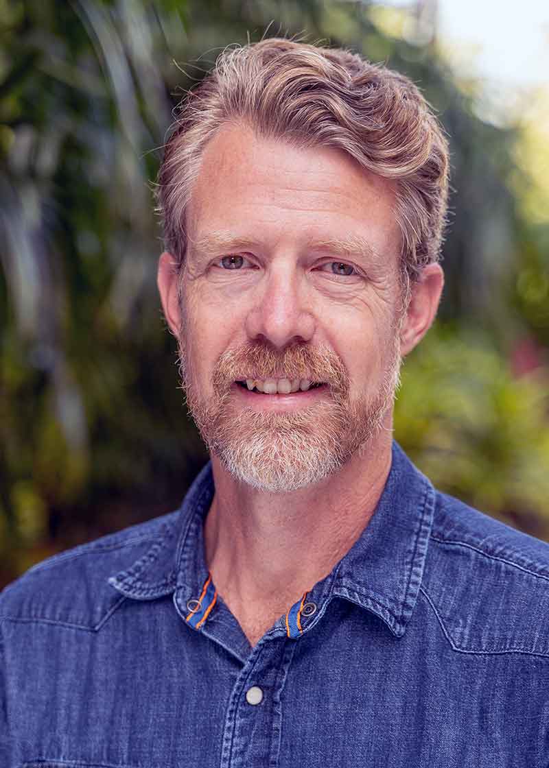 A man with white-and-red hair and facial hair in a blue button-down shirt