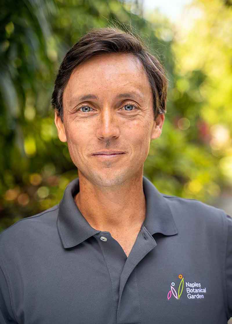 A headshot of a man in a grey polo and blue eyes