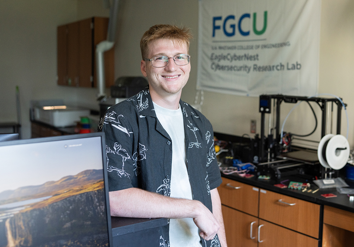 Man with glasses wearing a. black shirt and standing in a research lab