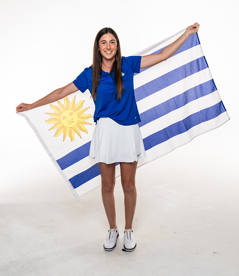Woman in blue top and white skirt holding a blue and white striped flag with a sun on it