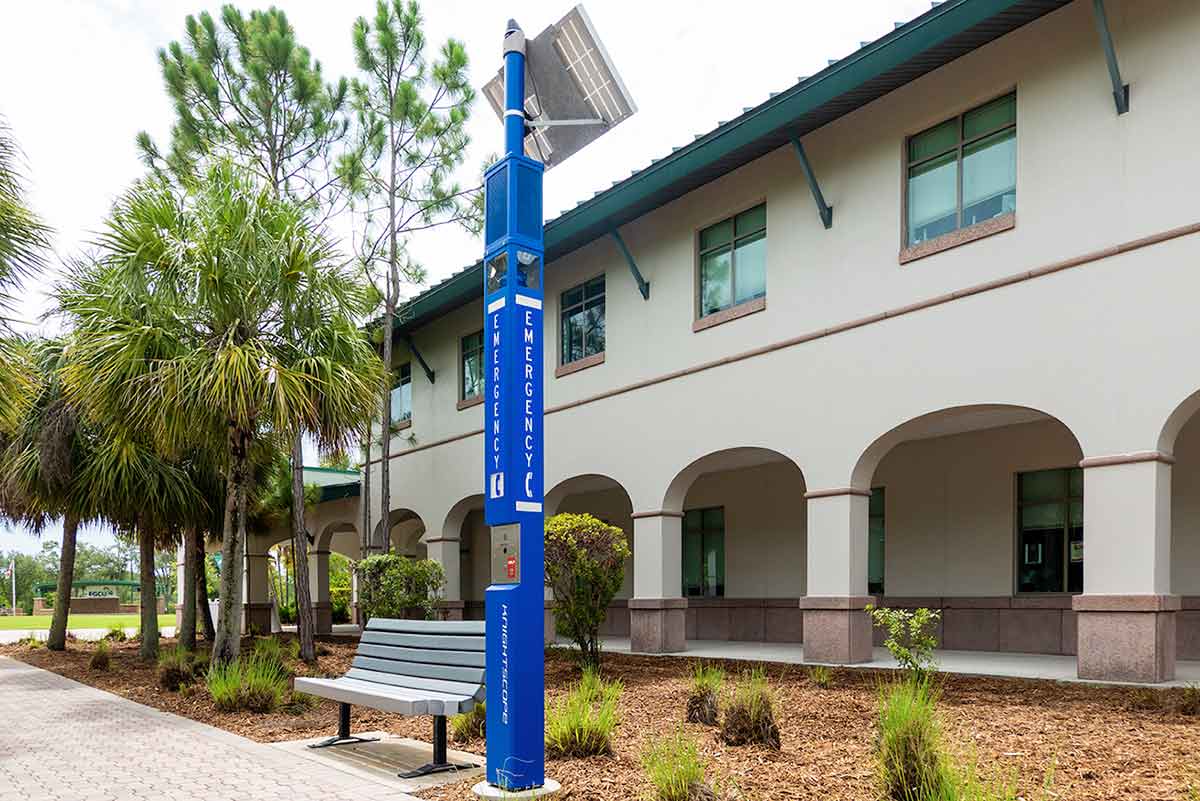 A long, blue pole in front of a green-roofed, two-story building