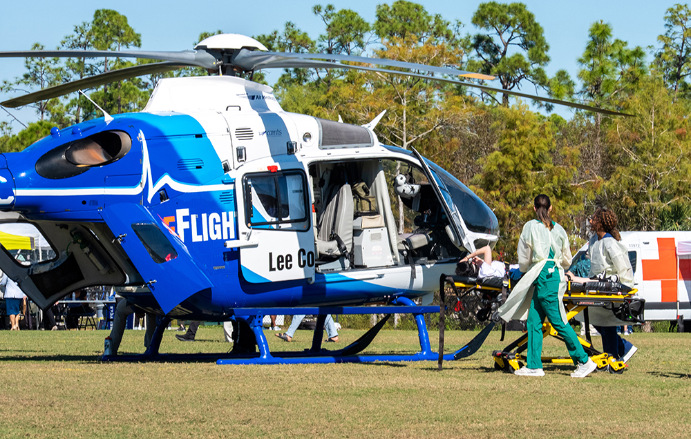 Medical team loads a patient onto a blue and white helicopter during emergency drill.