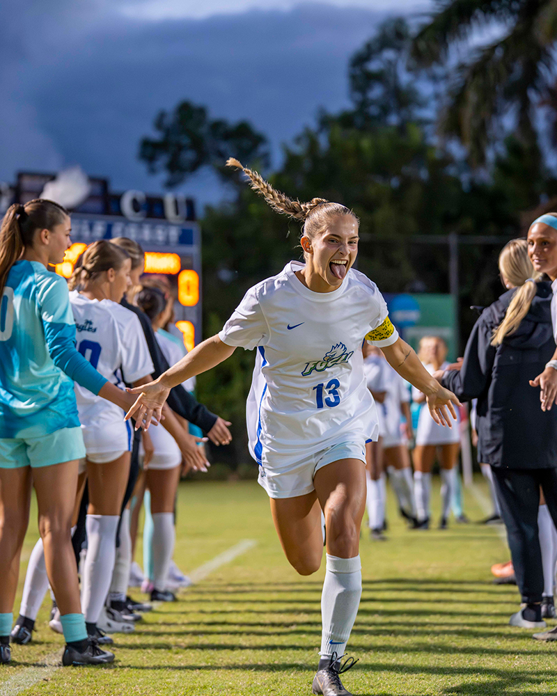 Soccer player runs through teammates forming a tunnel on the field