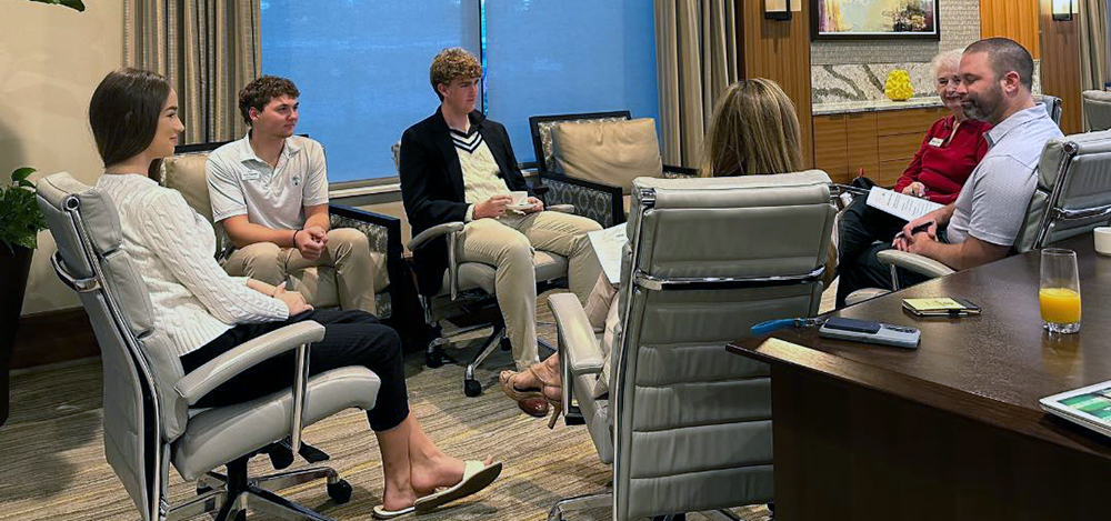 Group seated in office chairs having a discussion around a small table.