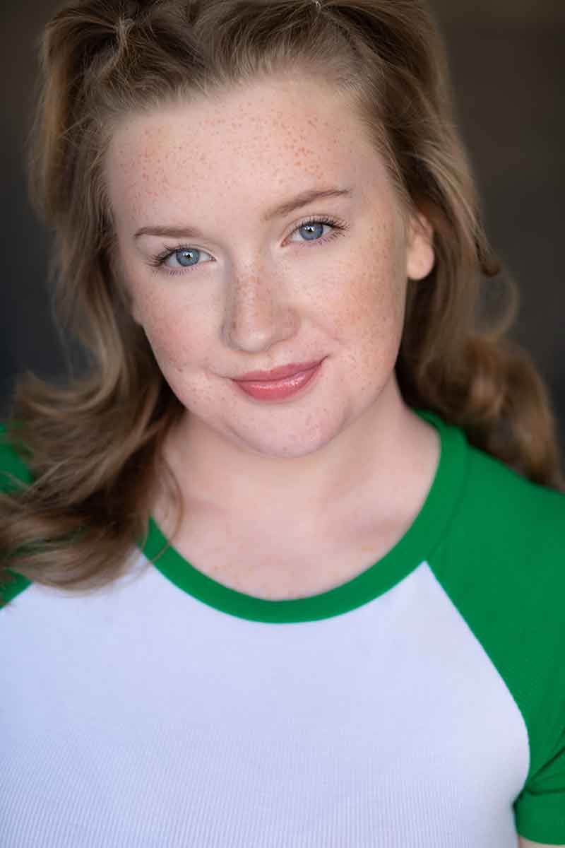 A headshot of a woman with blue eyes in a white and green shirt