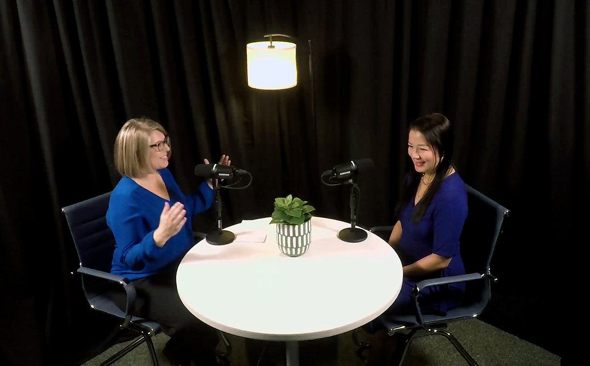 Two people recording a podcast at a round table in a studio with microphones and lights.