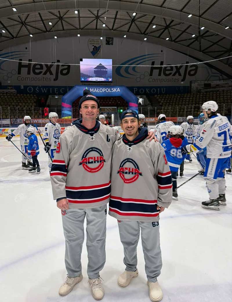Two hockey players pose on the ice in ACHA jerseys after a game.