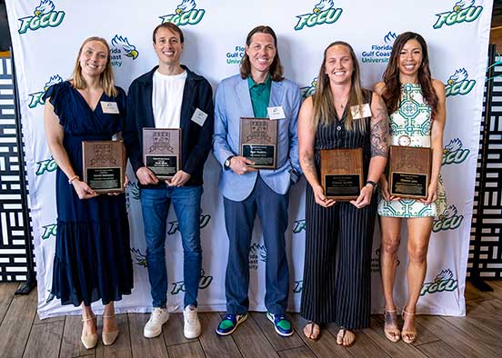 Five FGCU Athletics Hall of Fame inductees hold plaques before FGCU logo backdrop.
