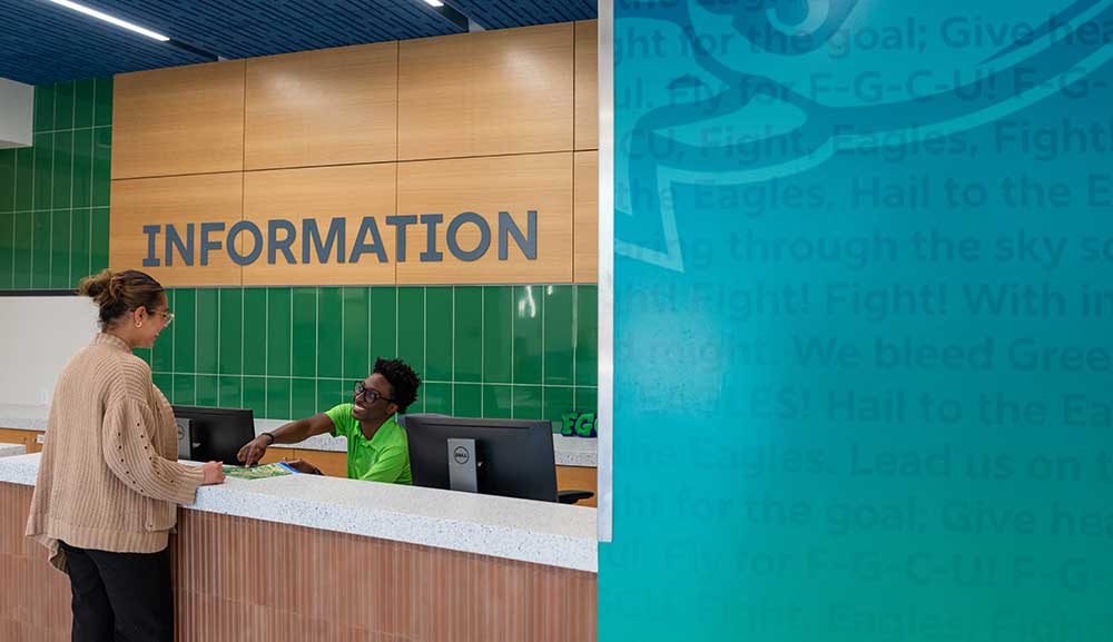 Person assists visitor at Information desk inside Cohen Student Union.