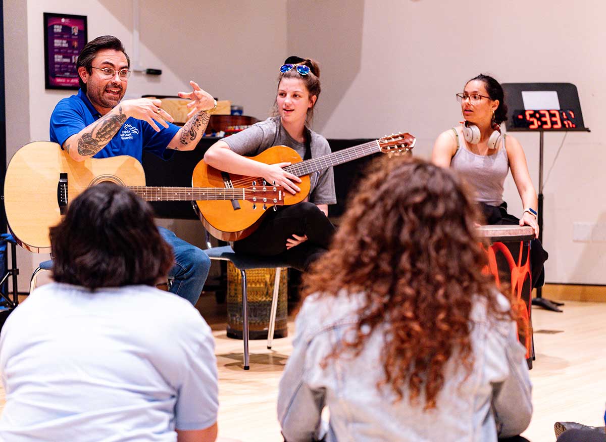 Group playing guitars and percussion during a music class