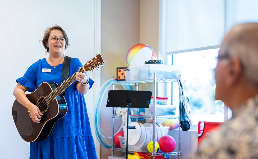 Person playing guitar during music therapy session with older adults
