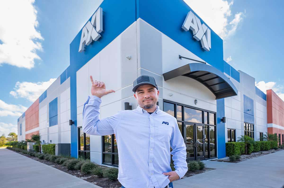 FGCU engineering alumnus stands outside AXI headquarters after career advancement