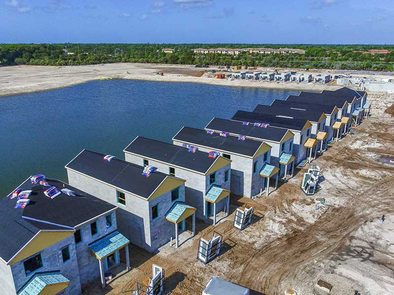 Row of Eagle View Village townhomes under construction beside retention lake