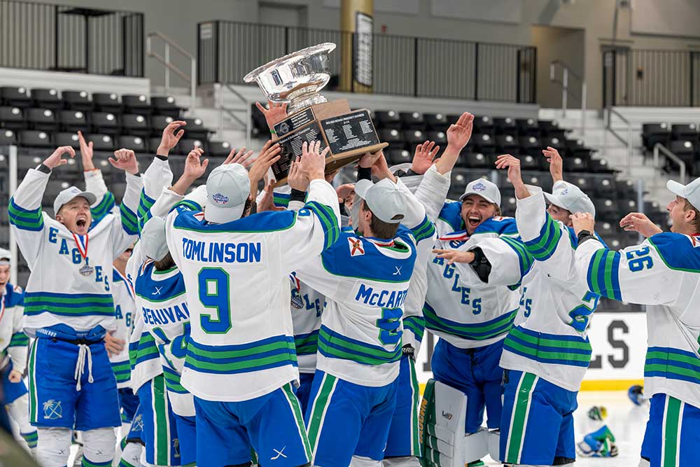 College hockey team hoisting championship trophy on ice