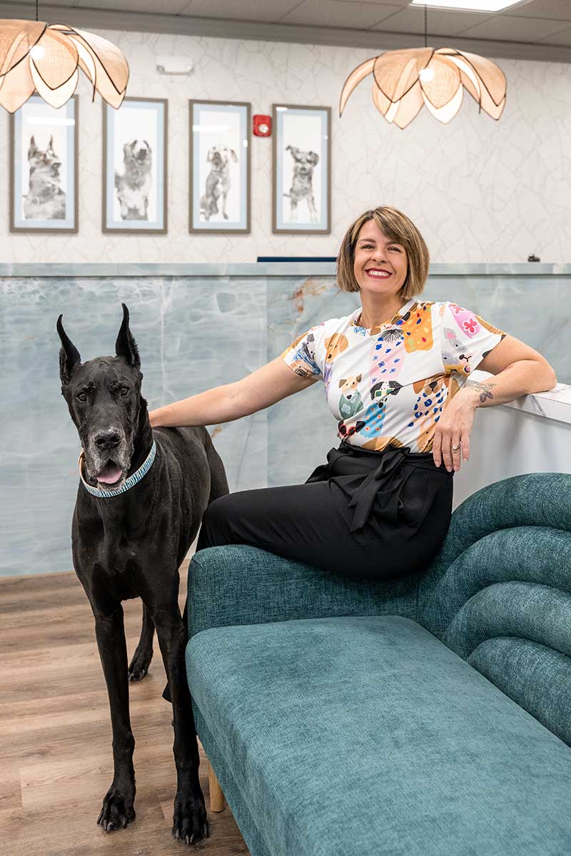 Veterinary clinic lobby with staff member seated beside large black dog