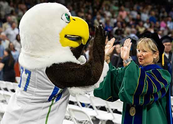 FGCU's Eagle mascot, Azul, high fives FGCU President Timur, in her green and dark blue regalia
