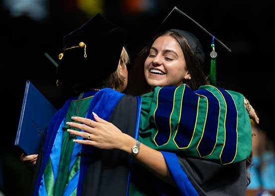 FGCU graduate embraces faculty member during commencement ceremony