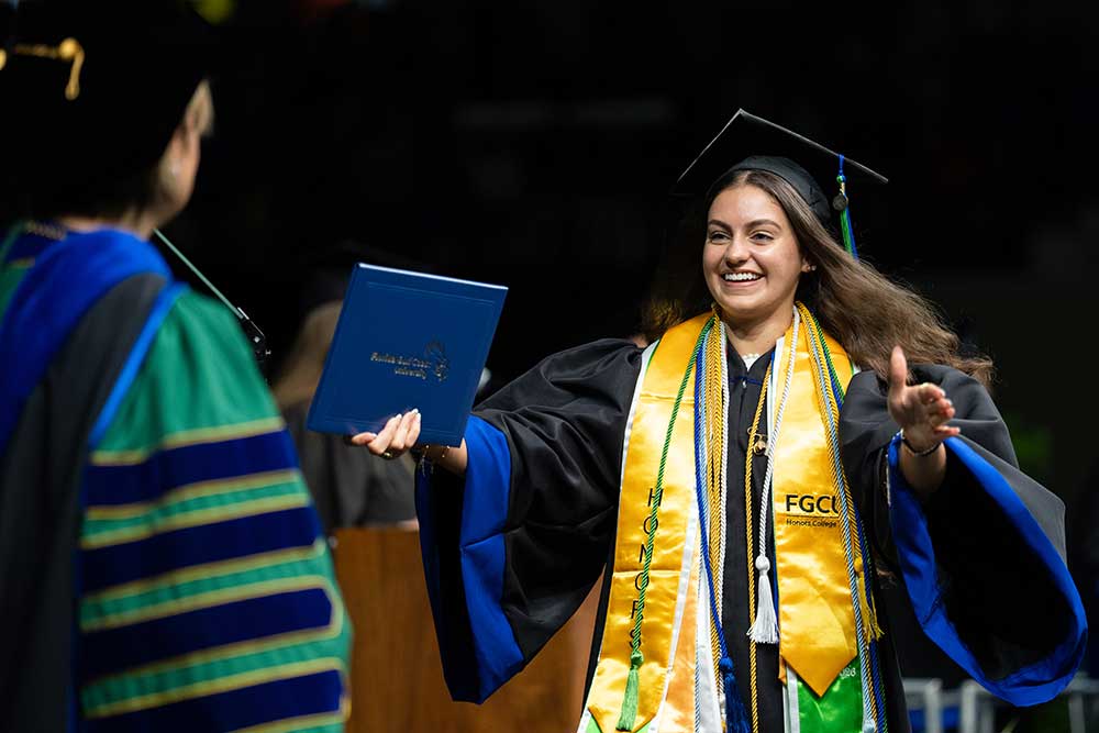 FGCU graduate receives diploma at commencement wearing honors cords