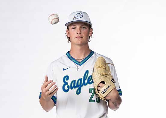 FGCU baseball pitcher in Eagles uniform tossing ball during studio portrait