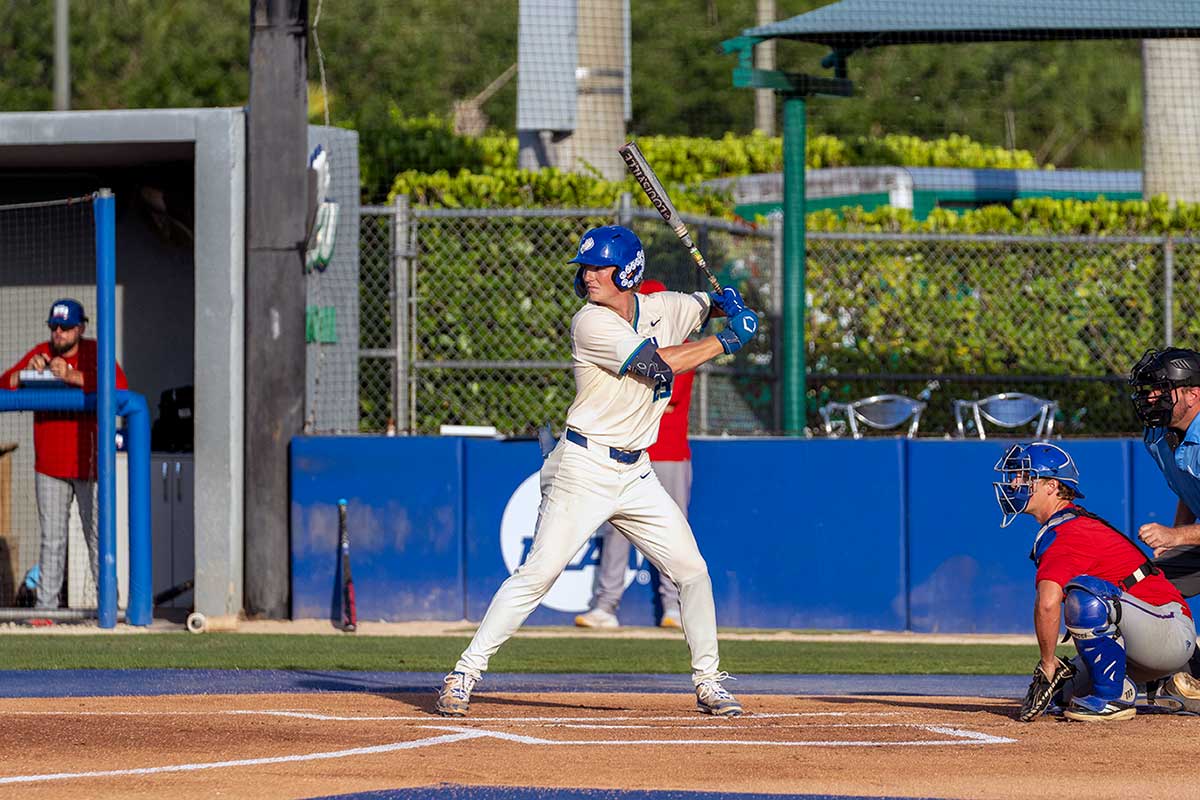 FGCU baseball player batting at plate during game with catcher and umpire